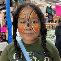 a girl with butterfly face paint at a market