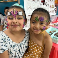 two girls posing for a photo at a face painting event