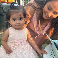 a little girl in a pink dress with a woman