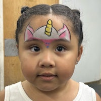 a little girl with a unicorn face painted on her face